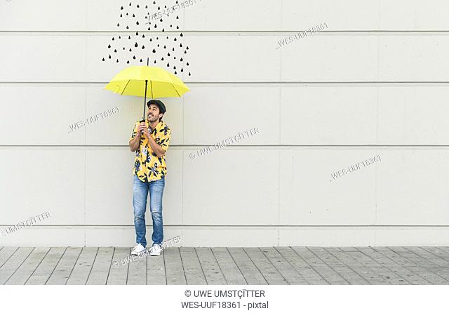 Digital composite of young man holding an umbrella at a wall with raindrops