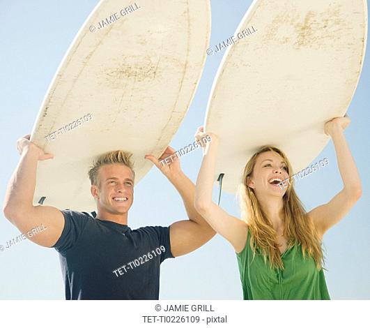 Couple holding surfboards on head