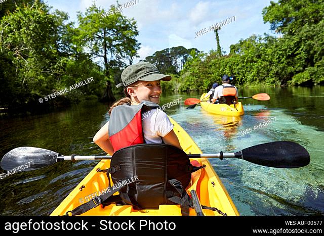 Smiling girl canoeing in lake during vacations