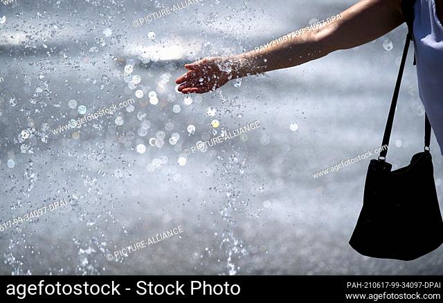 17 June 2021, Bavaria, Munich: A woman cools off at a fountain at Karlsplatz (Stachus). Photo: Sven Hoppe/dpa. - Munich/Bavaria/Germany