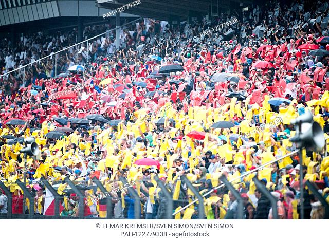 For the German Grand Prix the fans hold cardboard in the colors black, red and gold high, jubilation, cheer, cheering, joy, cheers, celebrate, fan, fans