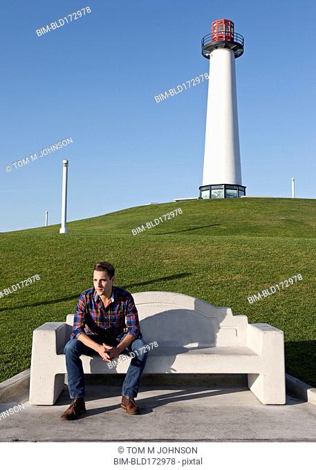 Man sitting on park bench near lighthouse
