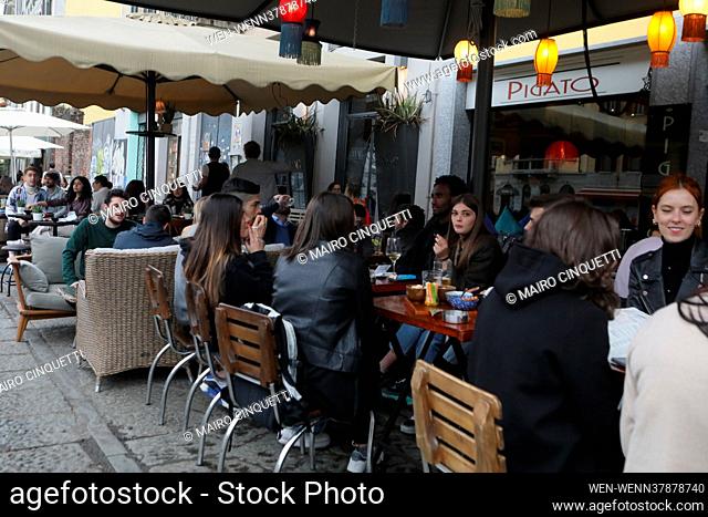 People have a drink on a bar terrace at the Navigli in downtown Milan on April 26, 2021 as bars, restaurants, cinemas and concert halls partially reopen across...