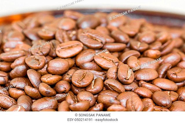 Close up roasted brown coffee beans in wood tray
