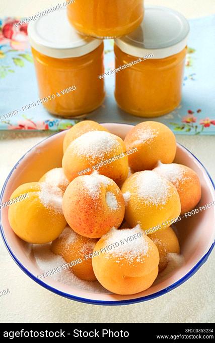 Apricots with sugar in bowl, jam jars behind