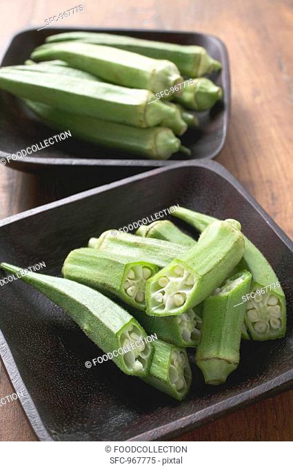 Several okra pods, whole & cut in two, in two dishes