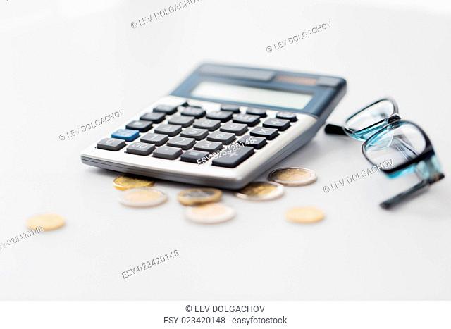 business, finance, money and bookkeeping concept - calculator, eyeglasses and euro coins on office table