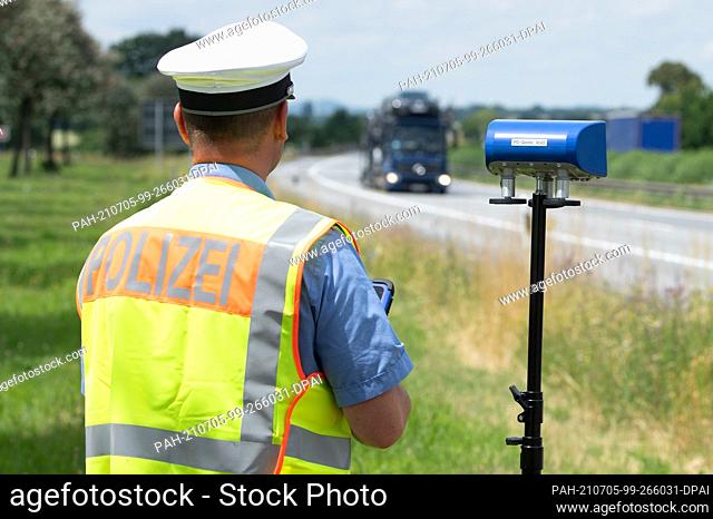 05 July 2021, Saxony, Bautzen: Tino Hausdorf, Chief Superintendent of Police, checks the information of the digital tachograph of a passing truck with a special...