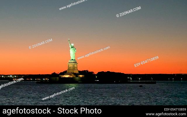 wide angle view of a beautiful sunset and the statue of liberty in new york