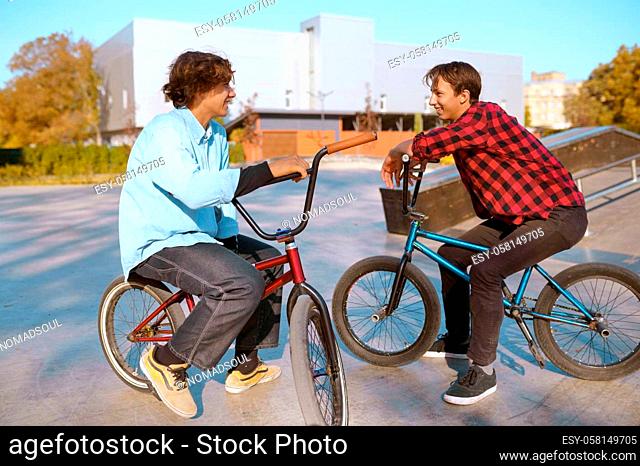 Bmx bikers on bikes, training on ramp in skatepark. Extreme bicycle sport, dangerous cycle exercise, street riding, teens biking in summer park