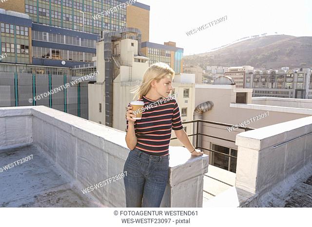 Young woman drinking coffee on a rooftop terrace
