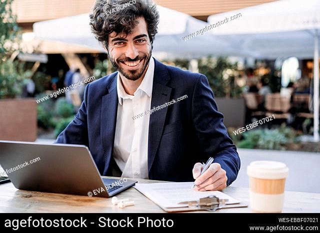 Happy businessman with laptop on table