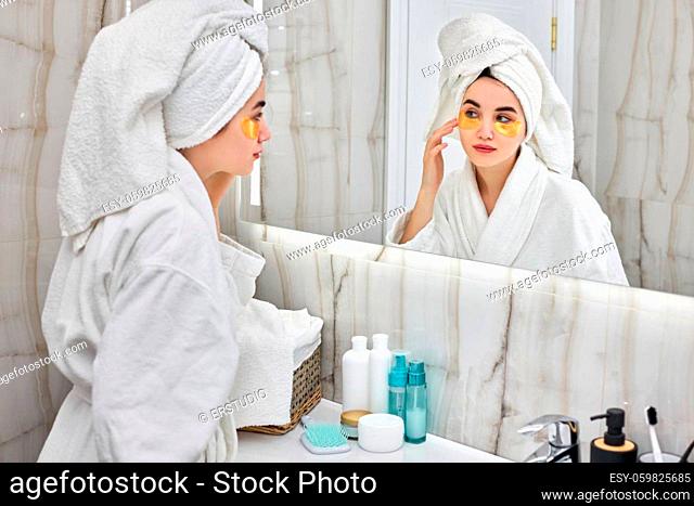beautiful woman with eye patches in white bathrobes in front of mirror in bathroom