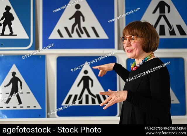 29 June 2021, Hessen, Kassel: The Kassel artist Doris Gutermuth stands in her studio in front of various crosswalk signs