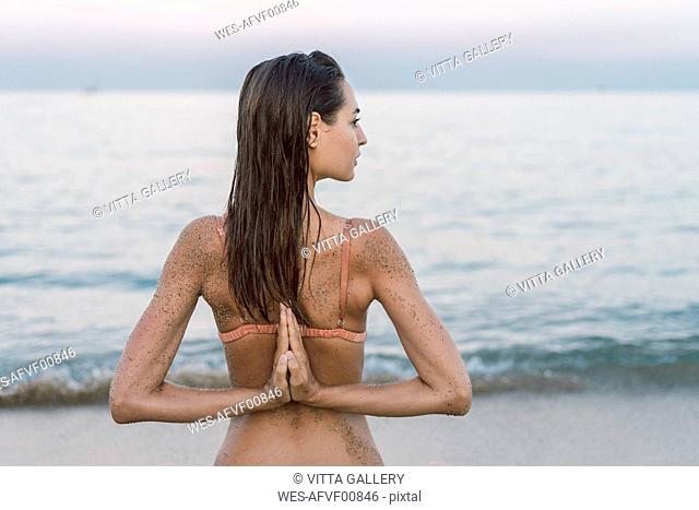 Beautiful woman on the beach practicing yoga