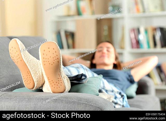 Happy woman resting at home with slippers on a couch