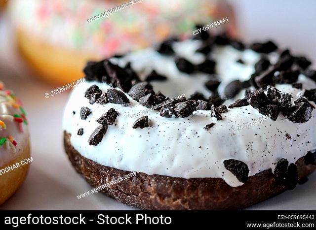 close-up of ring donut with white glaze sprinkled with black cookies