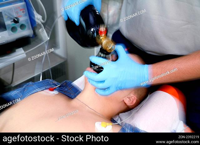 Sanitaeter beatmet einen Patienten mit einem Beatmungsbeutel, EKG ist angelegt. Paramedic performs artificial respiration, ECG is applied on the patient