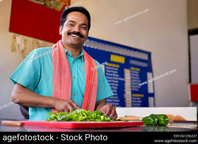Portrait of a Man chopping capsicum with knife in restaurant