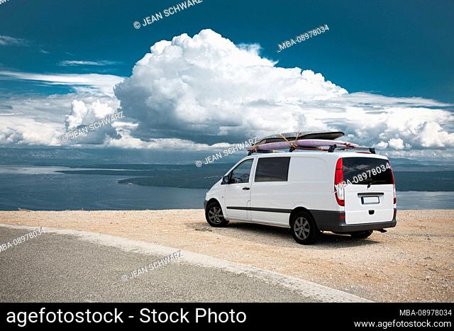 Van stands with surfboard on the roof at a lookout point on the island of Cres