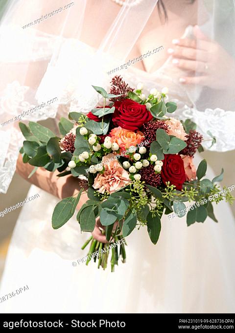 SYMBOL - 02 October 2023, Baden-Württemberg, Freudenstadt: A bride holds her bouquet before the beginning of a free wedding ceremony