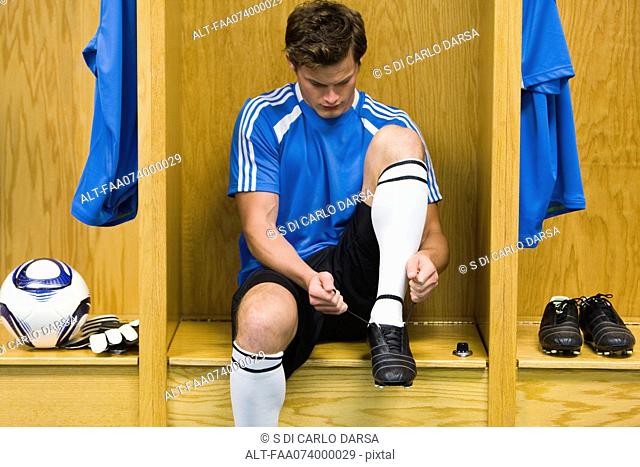 Young soccer player tying shoe