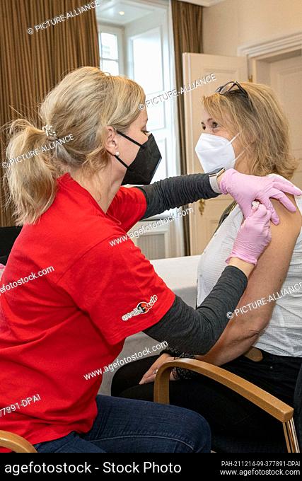 11 December 2021, Saxony, Dresden: A woman is vaccinated by the Dresden doctor Catherina Jürgens in the 5-star Grand Hotel Taschenbergpalais