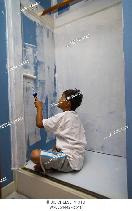 boy painting wall in closet