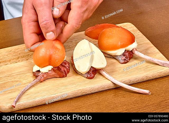cook prepares lamb ribs cooking process puts tomatoes on cheese lamb