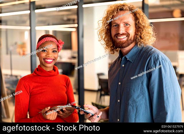 Portrait of smiling multiracial male and female colleagues with smart phones in office