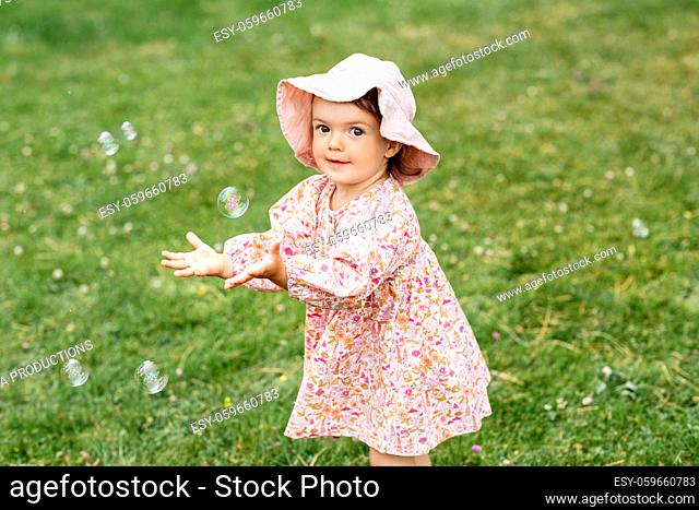 happy baby girl playing with soap bubbles outdoors