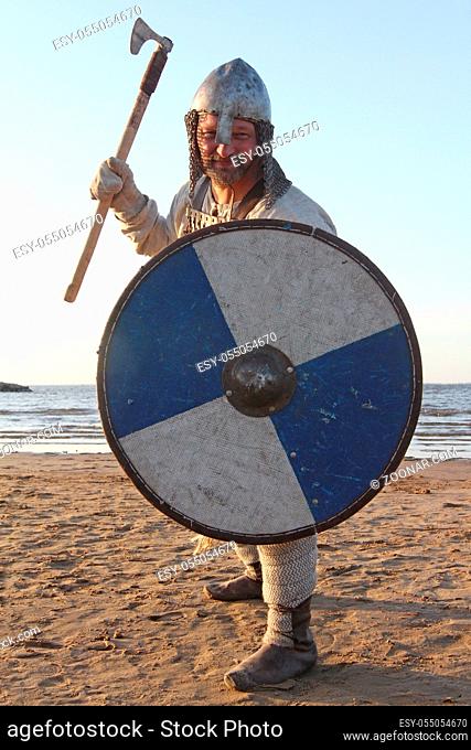 Portrait of slavic warrior reenactor with sword and shield posing outdoors at seaside