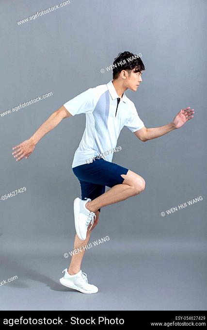portrait of fitness young man running on the gray background