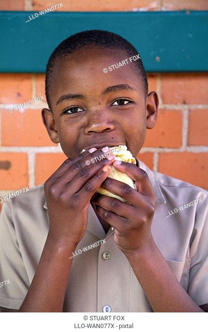 Young schoolboy eating a hotdog, Kwazulu Natal Province, South Africa