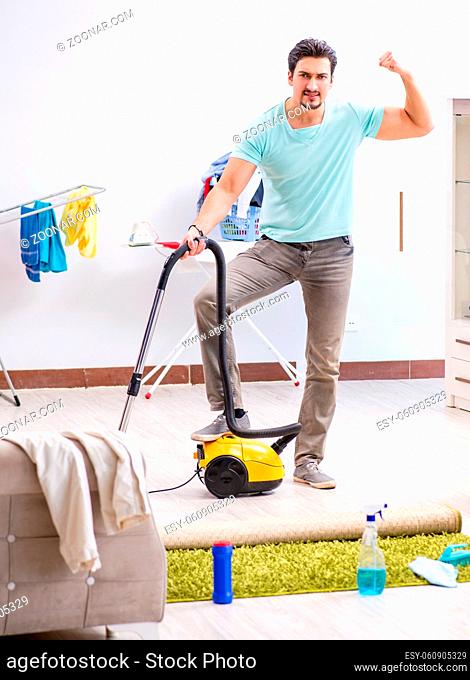 The young man husband doing vacuuming at home