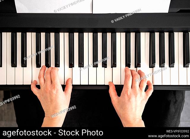 Mid adult woman playing piano notes at home