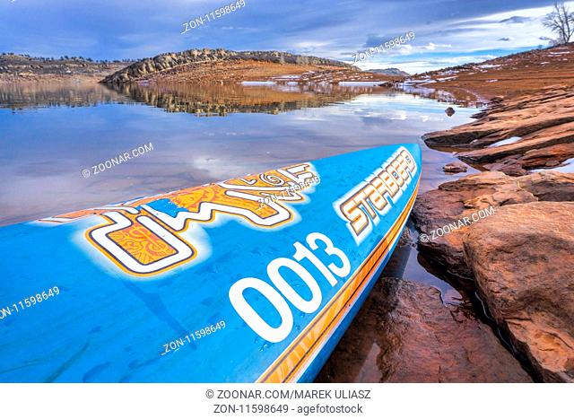Fort Collins, CO, USA - January 6, 2018: : A bow of All Star racing stand up paddleboard by Starboard with a race number on a rocky shore of Horsetooth...