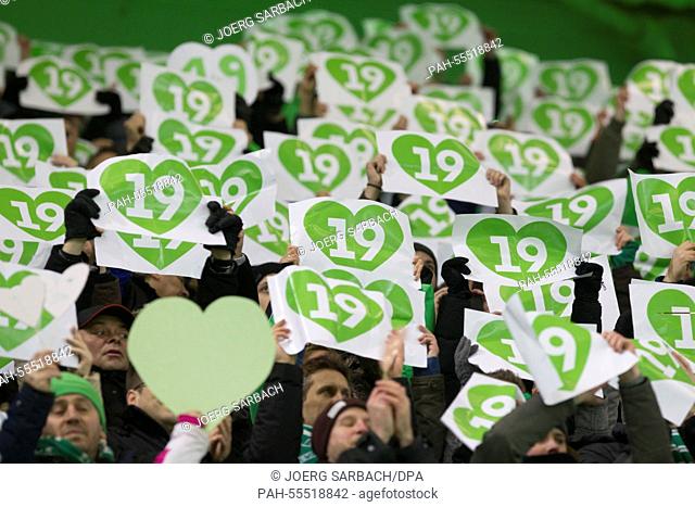 VfL Wolfsburg fans hold signs in their hands which read the no. '19' to commemorate Wolfsburg's late Junior Malanda prior to the Bundesliga soccer match between...