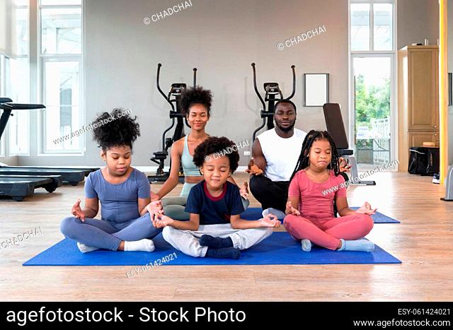 Happy family enjoy holiday together in fitness center. Meditating on yoga mat before exercise. Morning fitness, mindfulness concept