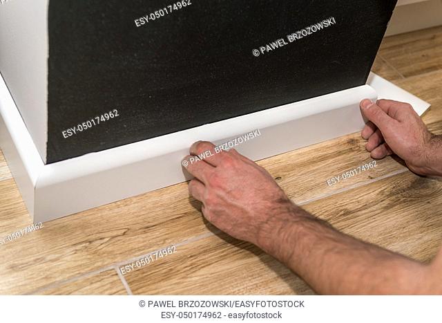 Close up of mans hands fitting skirting board