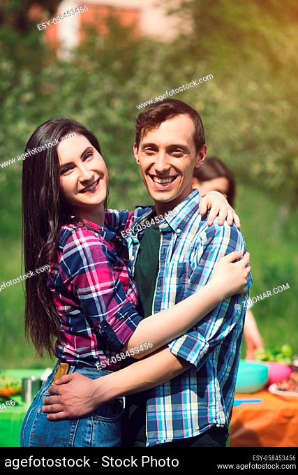 Joyful couple hugging and smiling. Happy guy and his girlfriend smiling genuinely looking straight into camera while hugging