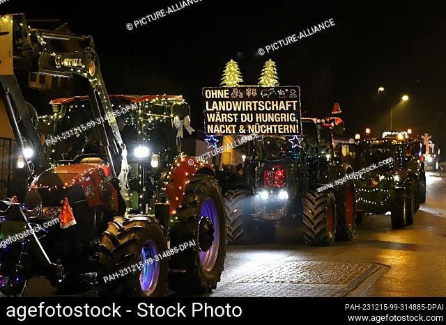 15 December 2023, North Rhine-Westphalia, Kürten: Tractors drive along a road illuminated with fairy lights during a tractor light drive