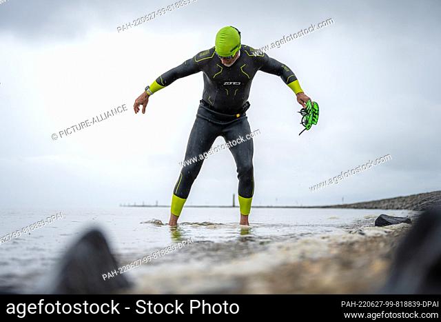 27 June 2022, Lower Saxony, Greetsiel: Frank Feldhus is standing in his wetsuit in the North Sea at Ley Bay in East Frisia