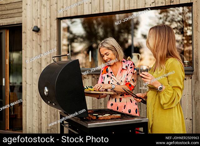 Smiling female friends preparing food on barbecue