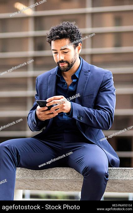 Male business person using mobile phone in city
