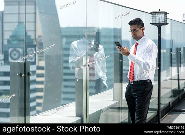 Businessman using a mobile phone on the top of a modern office building