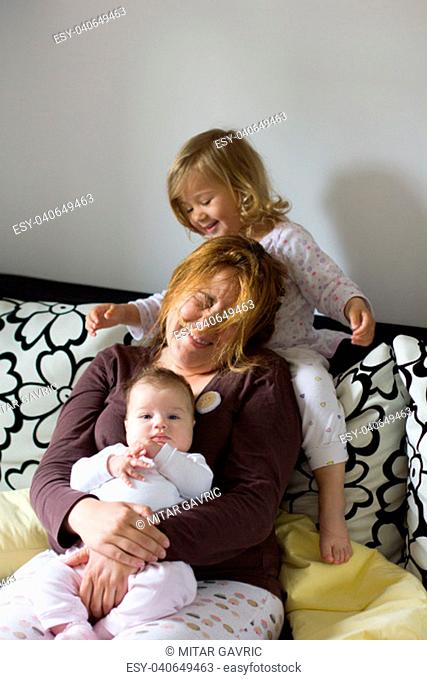 Happy Family at home, Young mother and her daughters, two years little girl and newborn baby