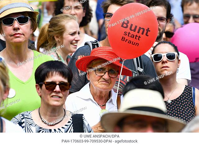 A woman holds up a balloon reading 'Bunt statt braun' (lit. 'Colourful instead of brown') during a counter demonstration against a demonstration of right-wing...