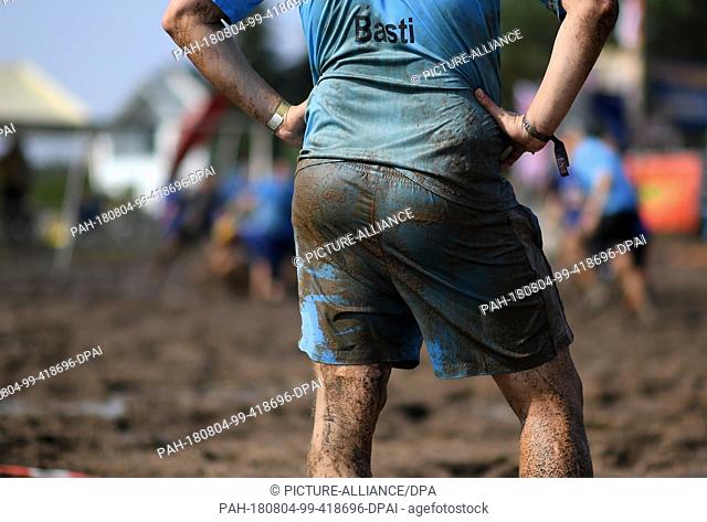04 August 2018, Germany, Woellnau: A team-mate of the German mud-football championship is waiting to play at the edge of a muddy field near Woellnau