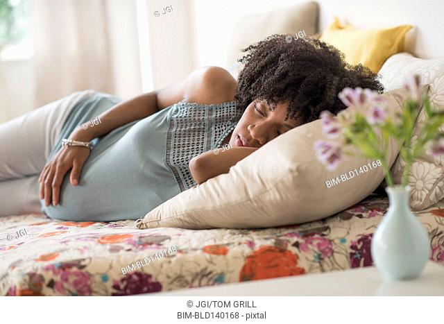 Pregnant African American mother holding her stomach in bed
